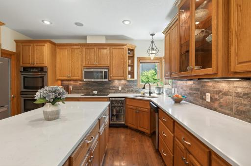 Chef's kitchen features large center island with counter seating, stainless steel appliances, a walk-in pantry and quartz countertops