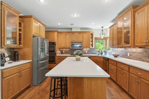 Chef's kitchen features large center island with counter seating, stainless steel appliances, a walk-in pantry and quartz countertops