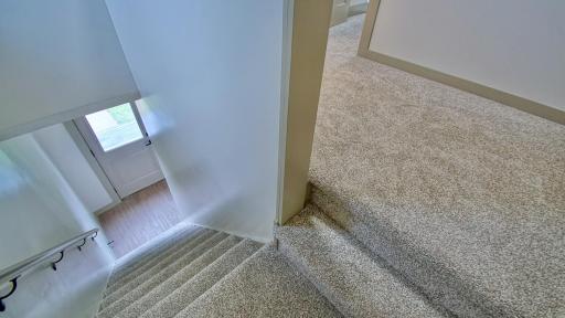 Stairs to upper level inside the front entry of home feature brand new carpeting.