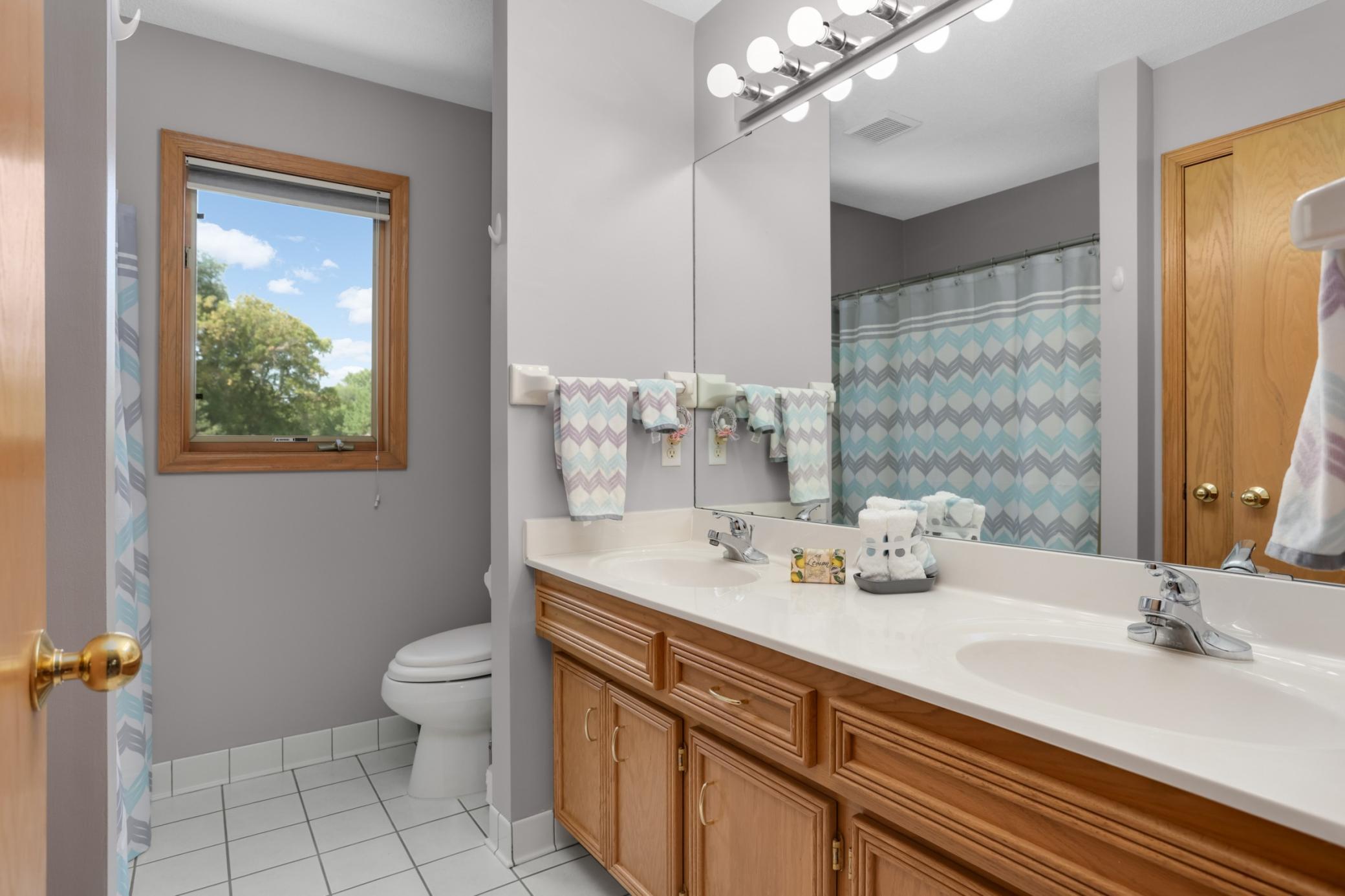 Full bath with double vanity and tiled floors.