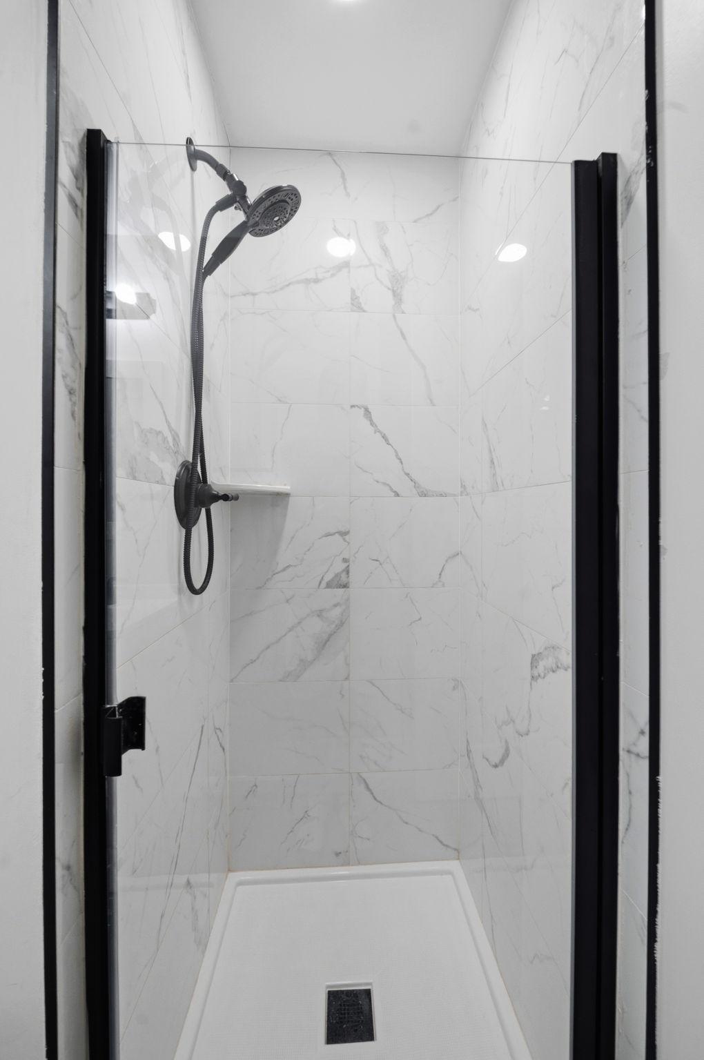 Private ensuite bathroom with tiled shower, glass enclosure, and modern black fixtures.