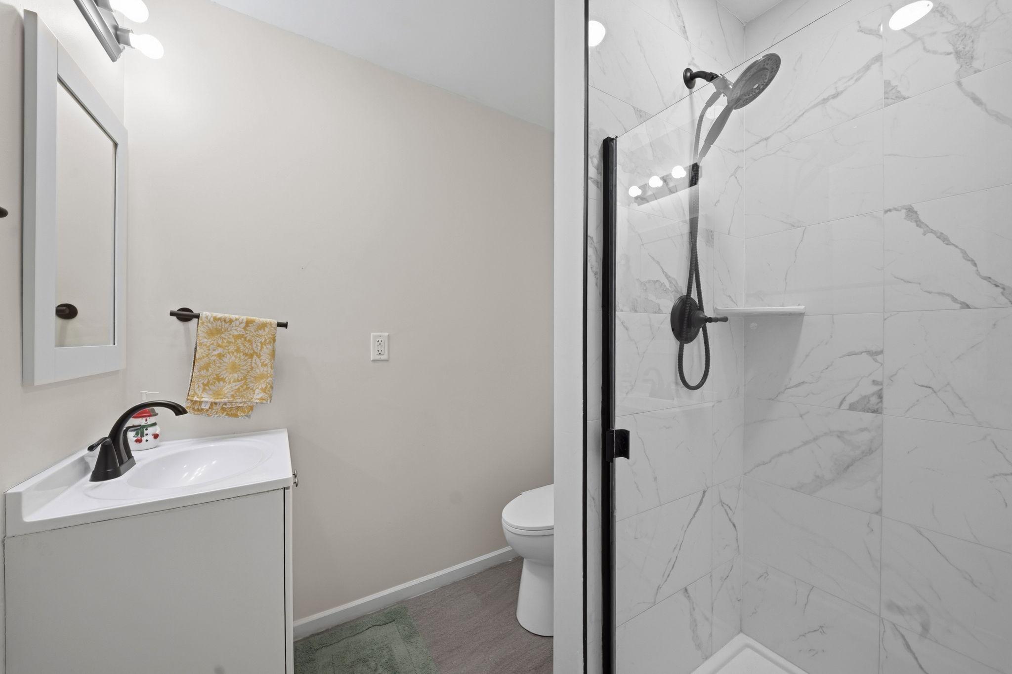 Private ensuite bathroom with tiled shower, glass enclosure, and modern black fixtures.