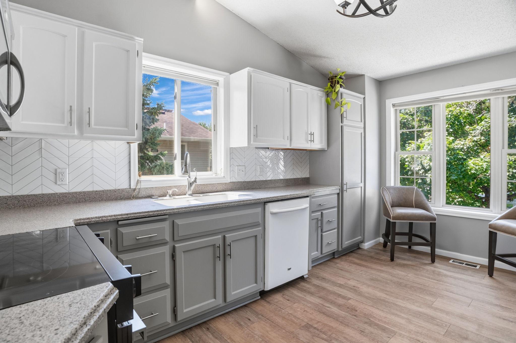 A bright, refreshed kitchen featuring two-tone cabinetry, ample counter space, and a stylish herringbone backsplash.