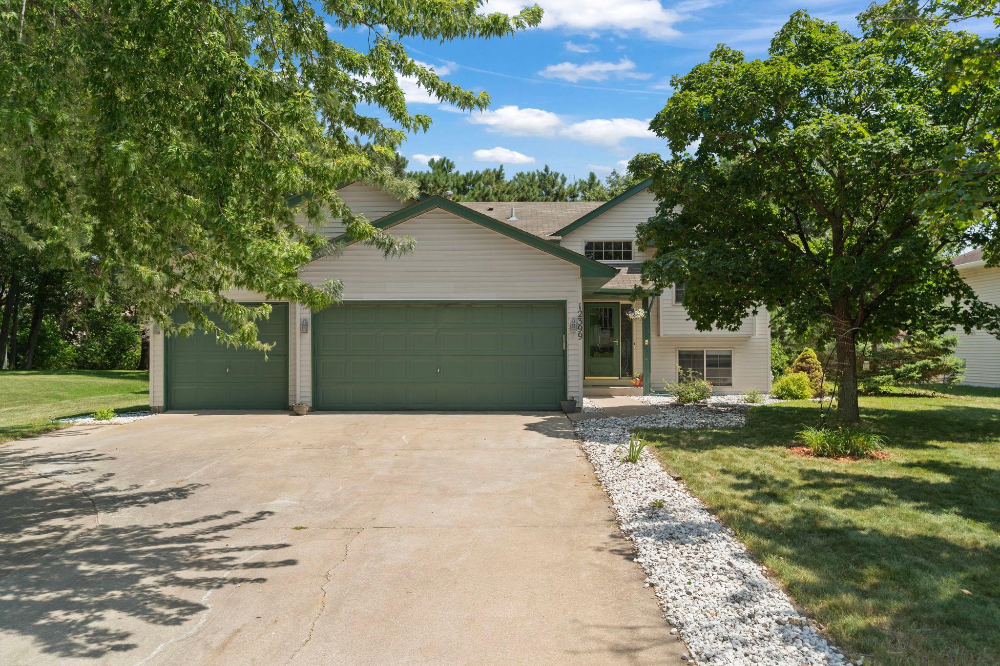 Welcome to 12399 Buchanan St NE in Blaine, featuring mature trees, attractive landscaping, and a spacious three-car garage.