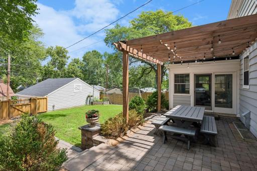 Large, fully fenced backyard features a new paver patio and walkway, pergola, and built-in grill with stone countertops.