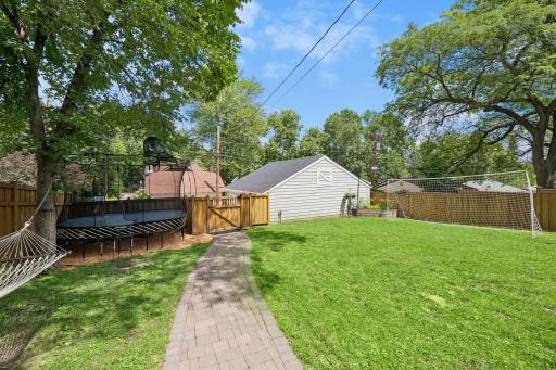 Large, fully fenced backyard features a new paver patio and walkway, pergola, and built-in grill with stone countertops.