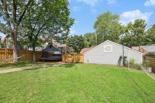 Large, fully fenced backyard features a new paver patio and walkway, pergola, and built-in grill with stone countertops.