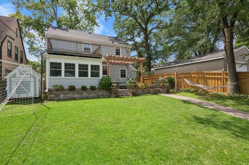 Large, fully fenced backyard features a new paver patio and walkway, pergola, and built-in grill with stone countertops.