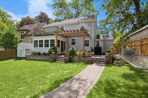 Large, fully fenced backyard features a new paver patio and walkway, pergola, and built-in grill with stone countertops.