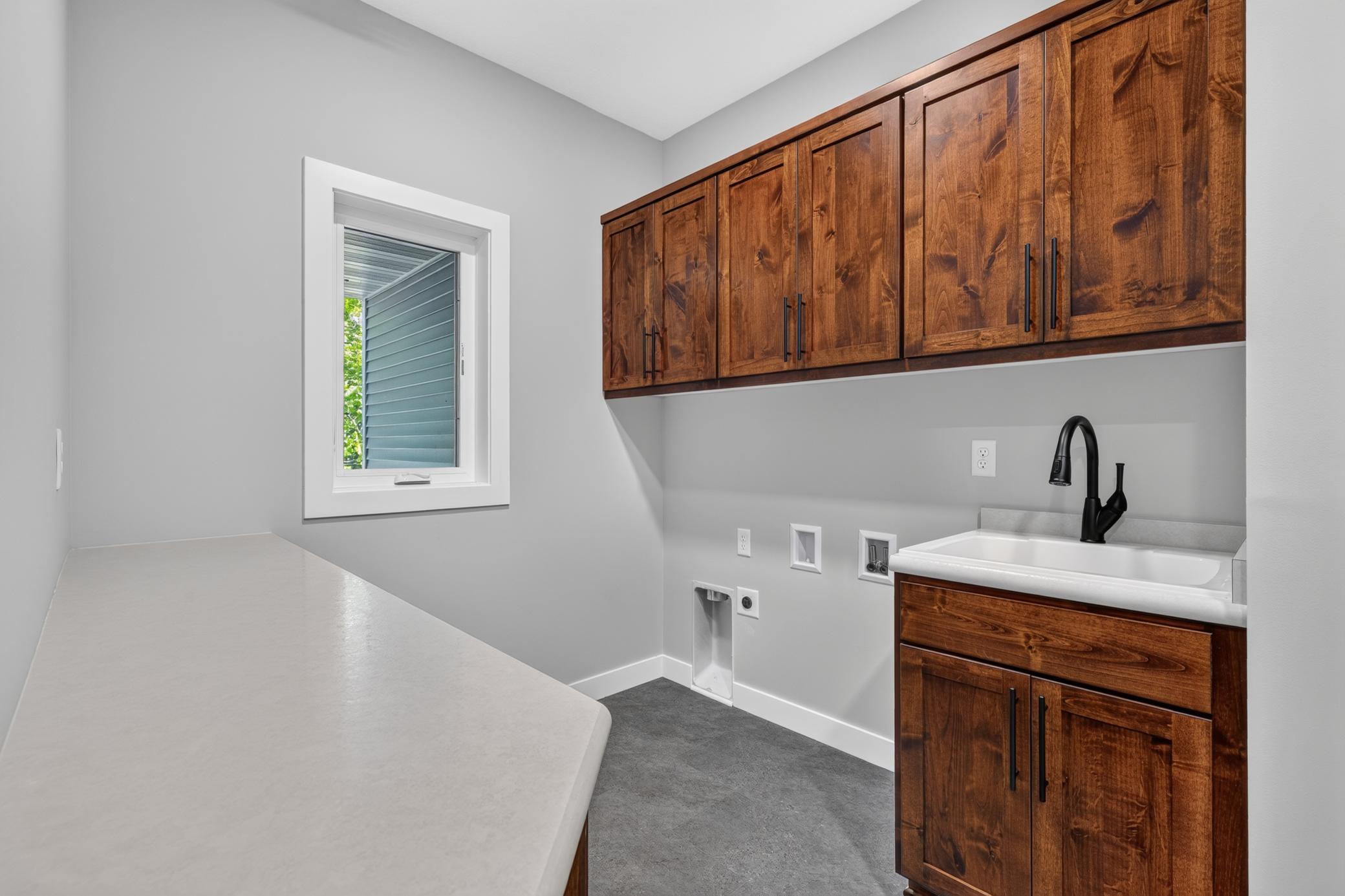 The laundry room features Custom Knotty Alder Cabinetry, a laundry sink, and lots of storage.