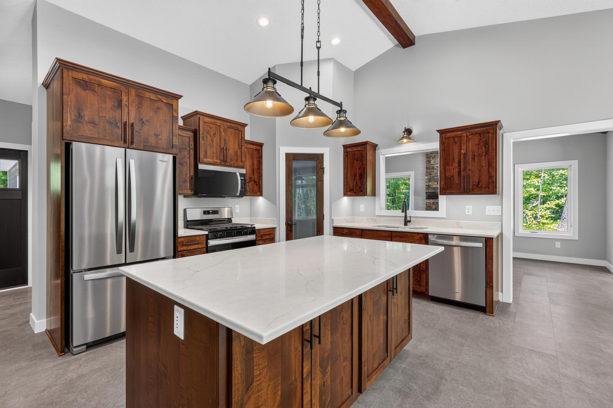 The kitchen features custom Knotty Alder Cabinetry with soft-close hardware and Quartz countertops along with stainless steel appliances
