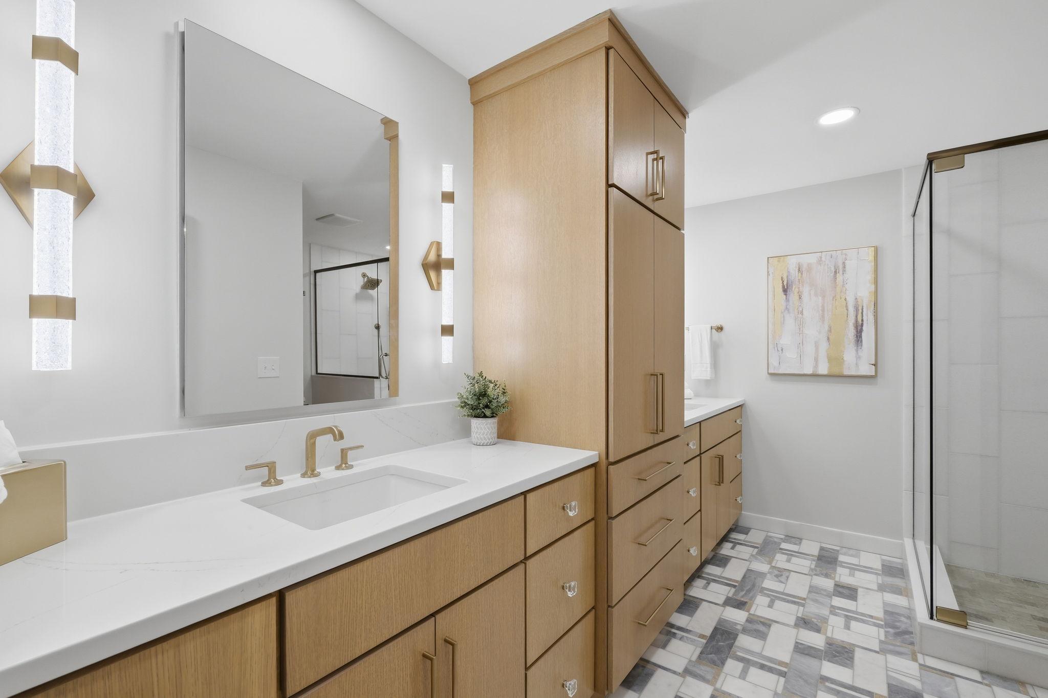 The Primary Bath features Versailles Marble flooring, marble shower walls, and double vanities with large flush mounted medicine cabinet mirrors