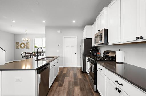 Gorgeous, expansive kitchen with quartz countertops, a large center island, gas range and tile backsplash.