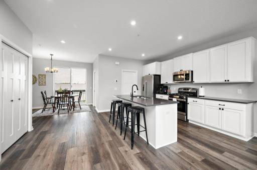 Gorgeous, expansive kitchen with quartz countertops, a large center island, gas range and tile backsplash. - Open Main Floor Plam!