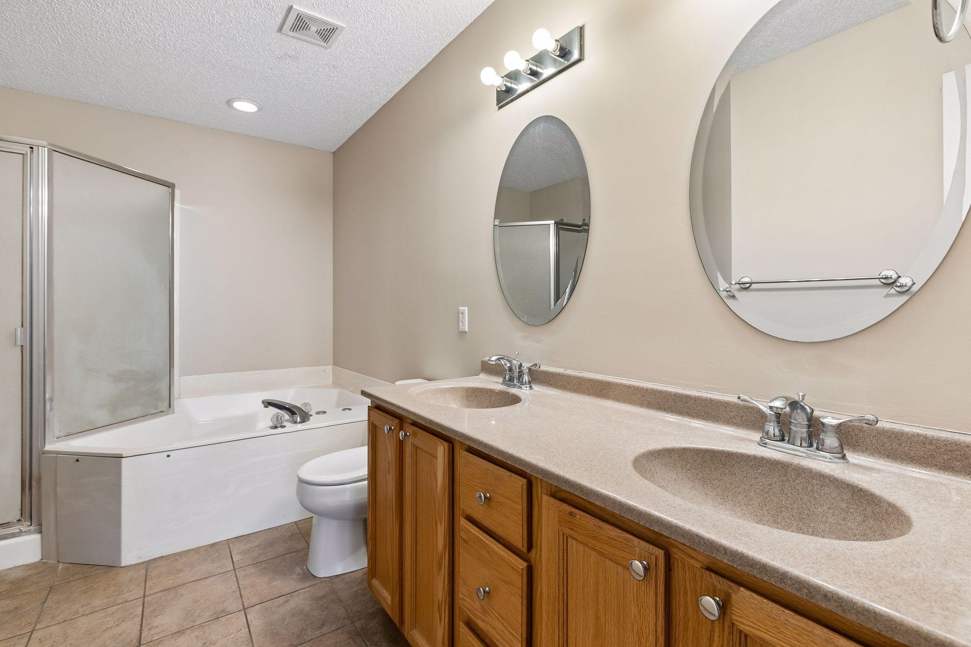 Upper full bathroom with dual sinks, tile floors, jetted tub, and walk-in shower