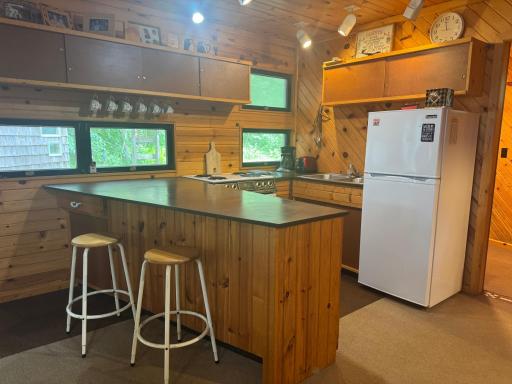 Step into a thoughtfully designed open kitchen that blends rustic charm with modern convenience. The space features warm wood finishes, compact yet efficient cabinetry, and clever storage solutions that make the most of every inch.