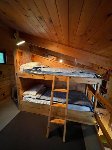 charming bunk room blends rustic warmth with practical comfort. Natural wood paneling creating a snug, retreat-like atmosphere, while the built-in bunk beds add both character and functionality.