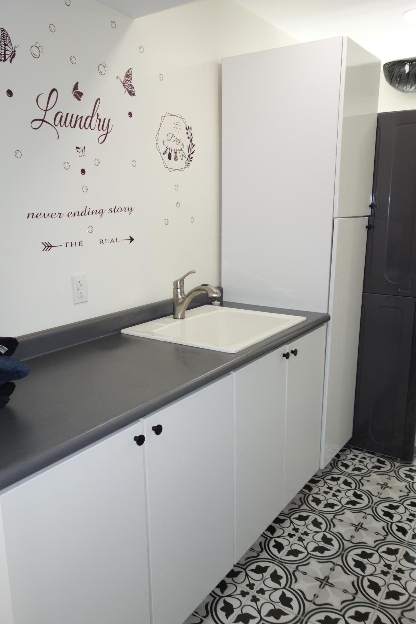 Utility sink and loads of cabinets in the lower level laundry.