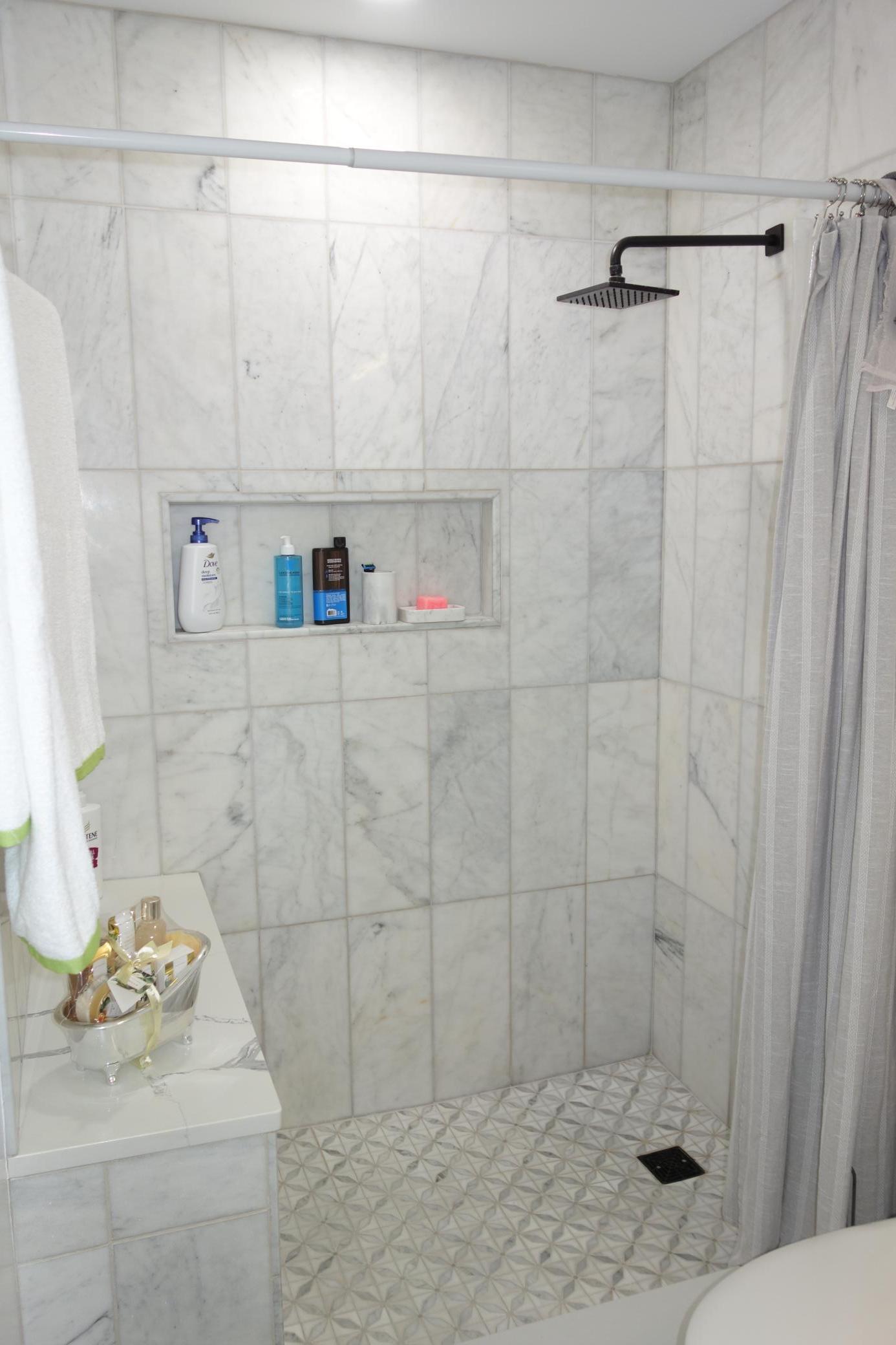 Beautiful tile walk-in shower with bench and shampoo storage.