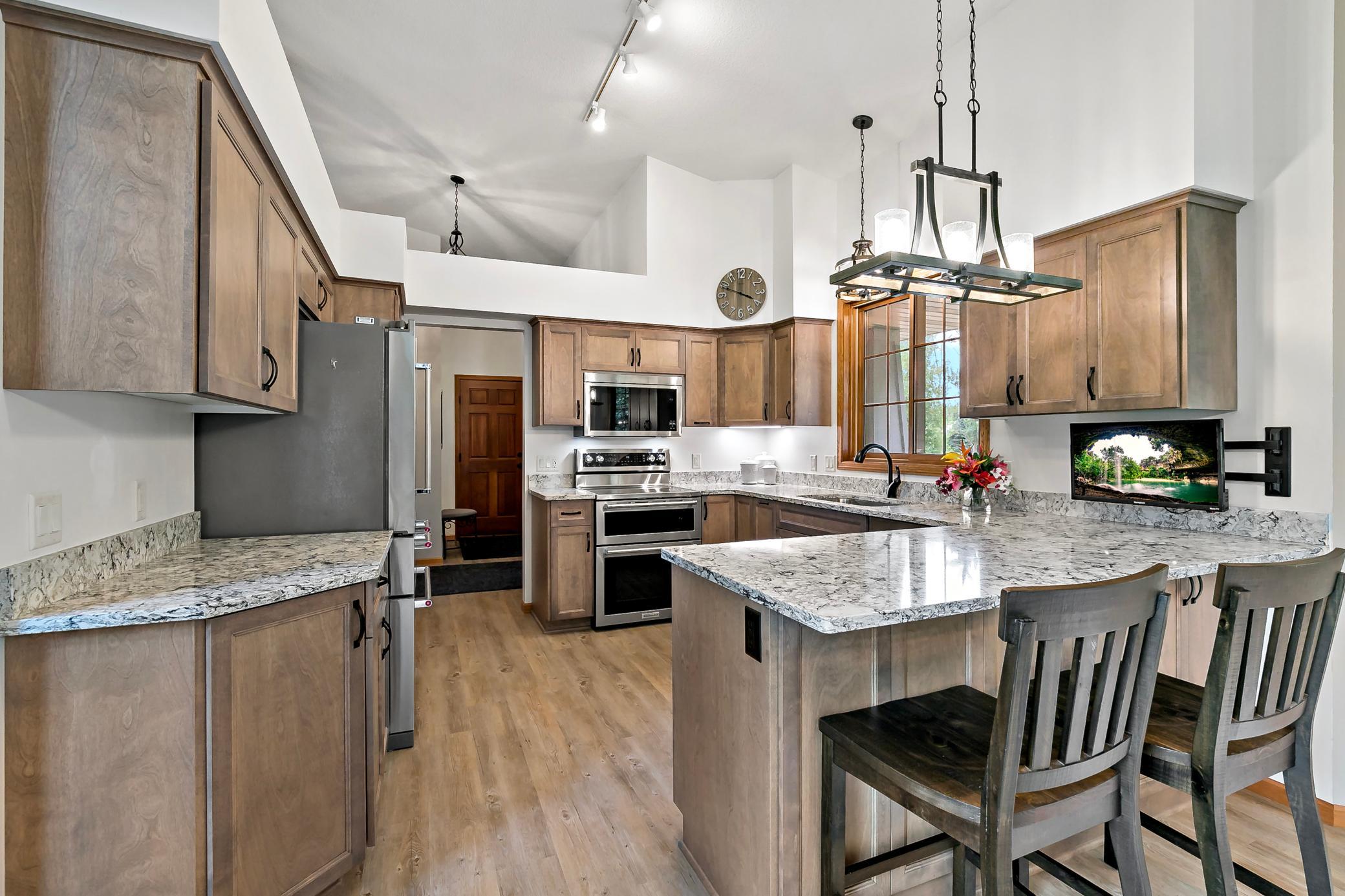 Impressive kitchen renovation in 2023 boast new stainless steel appliance, granite countertops, updated lighting, gray washed cabinetry, and LVP flooring.