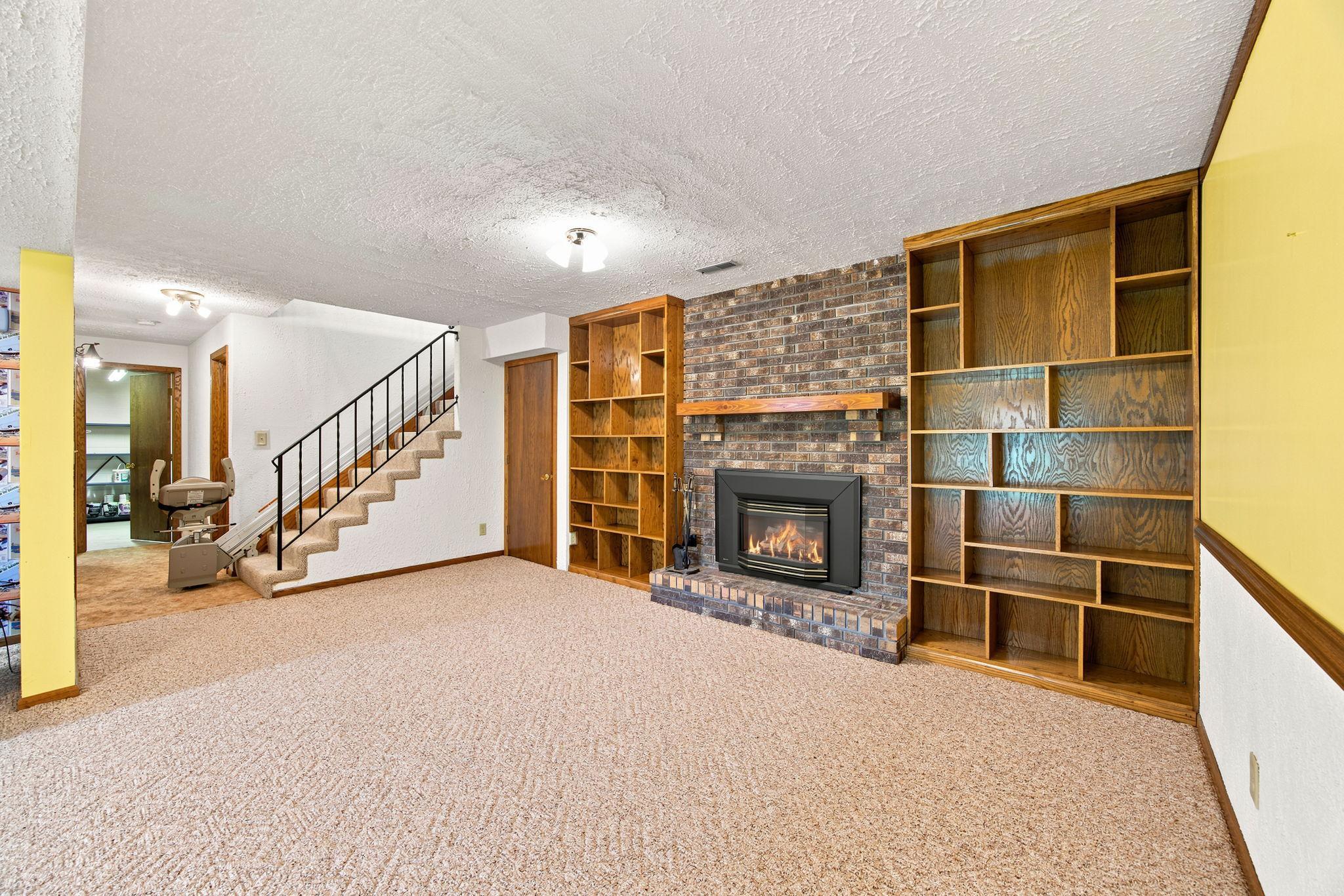 Gas fireplace has brick surround and built in bookshelves.