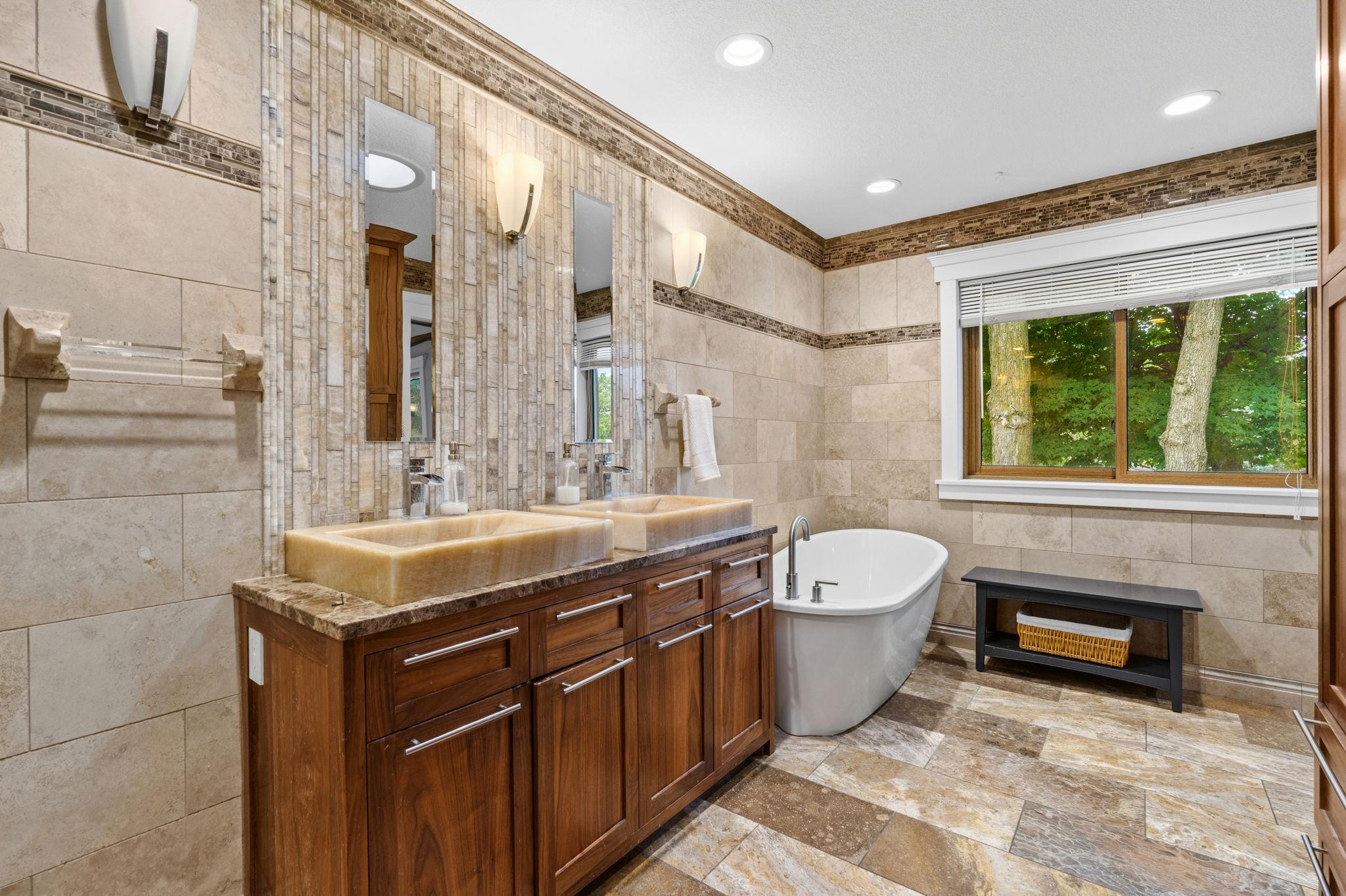 Additional view of double vanity and freestanding tub.