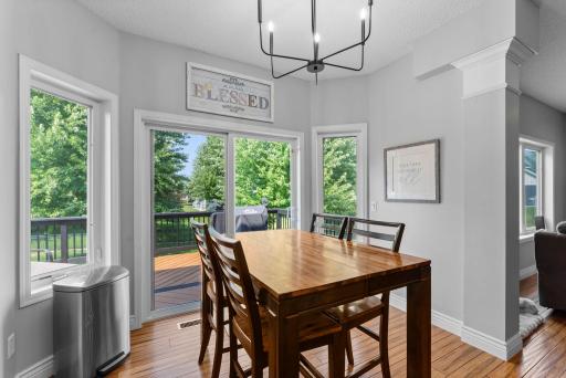The adjoining informal dining area showcases statement lighting, expansive windows, and connects seamlessly to the deck for indoor outdoor flow.