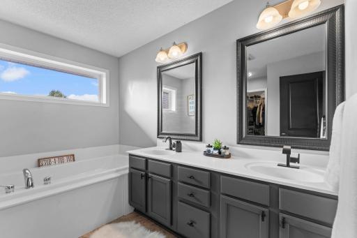 The ensuite bathroom features a double vanity, soaking tub, tiled walk-in shower, and tile flooring.