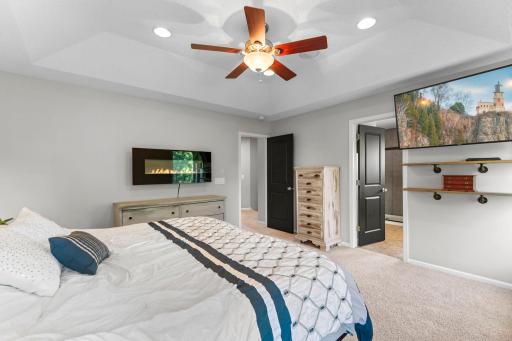 The private primary suite has a coved ceiling, ceiling fan, a large walk-in closet, and an electric fireplace for added comfort.