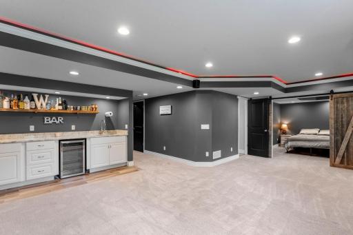 A wet bar with floating shelving and a beverage refrigerator makes hosting easy.