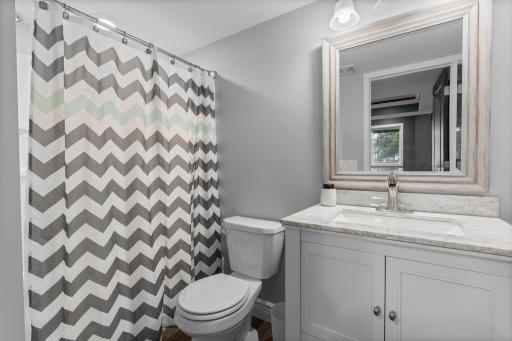 Nearby, the lower-level bathroom offers a walk-in shower and heated tile floors. A large finished storage area beneath the stairs adds storage versatility.