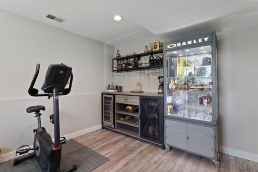 The family room features a dedicated entertaining area with luxury vinyl plank flooring, currently set up as a bar/workout area.