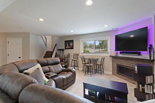 The lower level family room features a corner fireplace with stacked stone tile added in 2018. Updated with smooth ceilings (popcorn removed), recessed lighting, new carpet, fresh paint, and new trim for a modern, move-in ready feel.