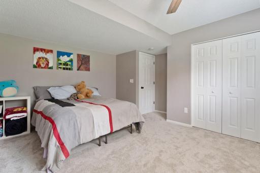 One of the lower level bedrooms is impressively large and filled with natural light, offering beautiful backyard views. It features fresh paint, carpet, ceiling fan with remote, and an upgraded closet organization system for excellent storage.