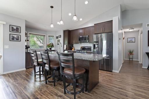 Luxury vinyl plank flooring flows through the open kitchen with vaulted ceilings and a bright bay window breakfast nook, complementing the granite island, slate appliances, and soft close doors cabinetry. The gas range (2024), has wi-fi & air fryer!