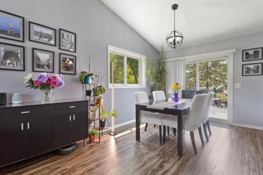 Dining room with luxury vinyl plank flooring, vaulted ceilings, and easy access to the deck. Spacious layout accommodates a large table. All windows in the home were replaced (2019-2022), with exception of bay windows.