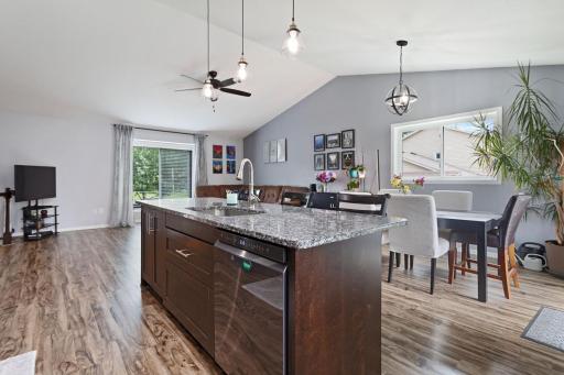 The sun-filled living room with vaulted ceilings, luxury vinyl plank flooring, and a large front picture window that fills the space with natural light. The open layout creates a bright, connected flow to the rest of the home.