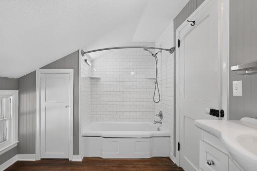 The bath and shower is tiled to the ceiling with white subway tile.