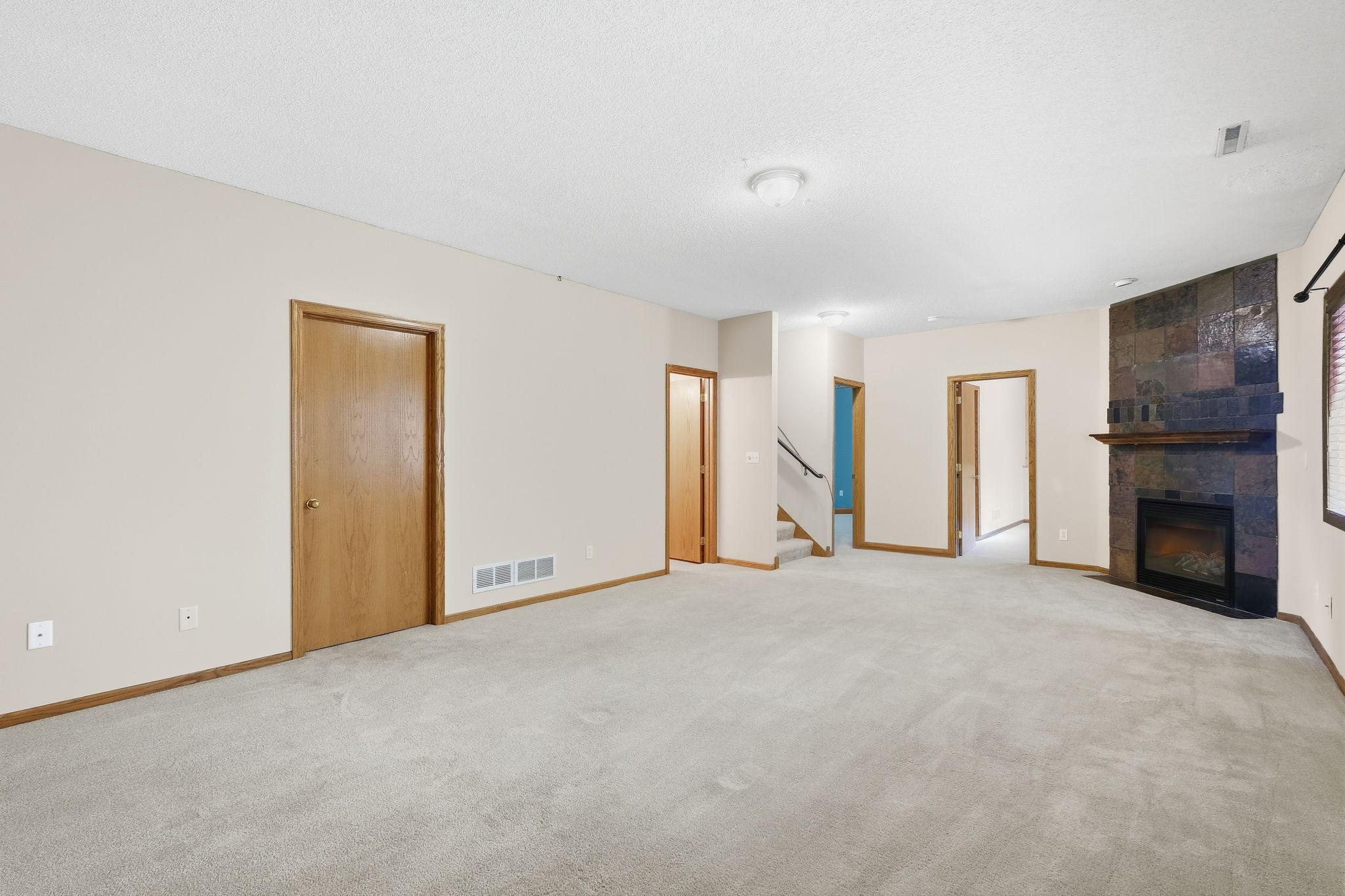 Spacious walkout lower-level family room featuring a cozy gas fireplace, perfect for relaxing or gathering with family and friends.