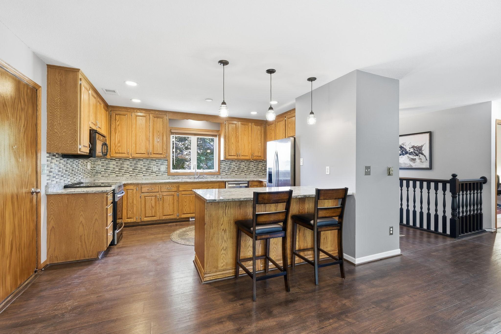 Functional kitchen featuring granite countertops, a tile backsplash, and a convenient eat-in breakfast area.