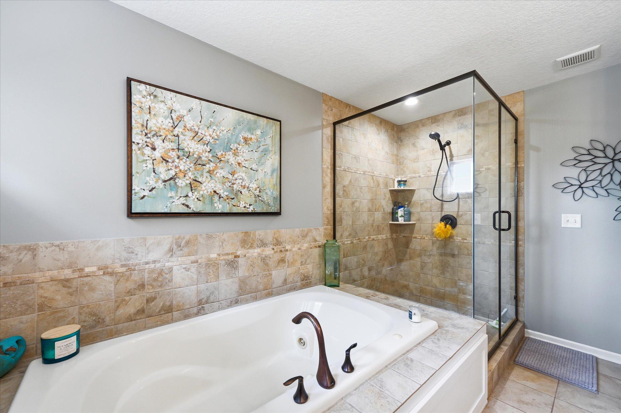 Primary suite bathroom with tub and shower