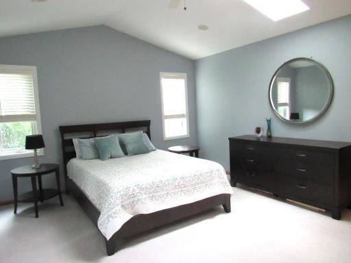 Partial view of the vaulted primary bedroom with recessed lighting and a sky-light.