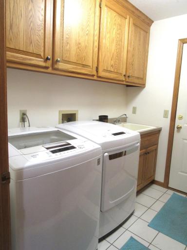 Main floor tiled laundry with cabinets and a deep double closet.
