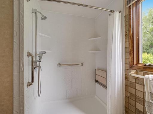 Main floor newer handicap accessible low step-in shower with flip down seat in back right.