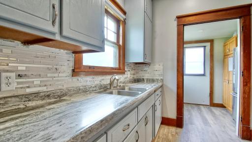 Kitchen with new tile backsplash and luxury vinyl plank flooring in 2026. Back entry into home is through the doorway straight ahead.