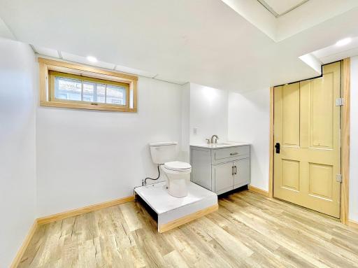 1/2 Bath on lower level has new vinyl planking, new vanity and freshly painted walls. The utility room is through the closed door on the right. New furnace, A/C, and ductwork in 2022.