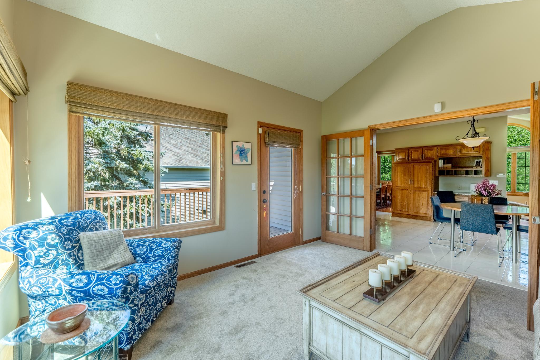 The sunroom, with new carpet, extends your living space, surrounded by windows and leading to the deck.