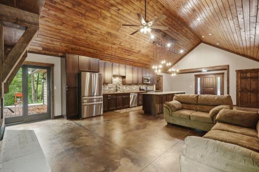 Stained pine tongue & groove vaulted ceilings with recessed lighting, hanging light fixtures over the kitchen island and ceiling fan.