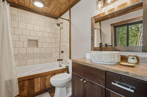 Features Jacuzzi tub, Travertine tiles, stained wood accents, custom vessel sink and butcher block countertop