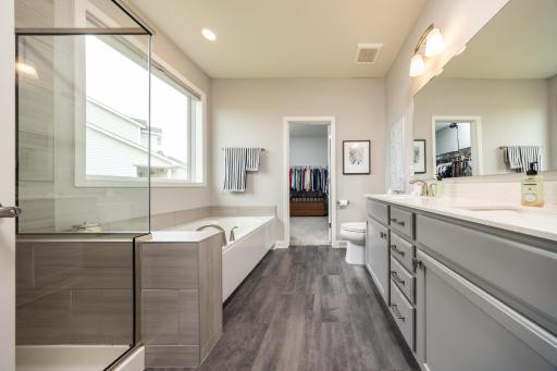 The spacious private primary bathroom features dual vanities, a soaking tub, separate shower, and an oversized walk-in closet